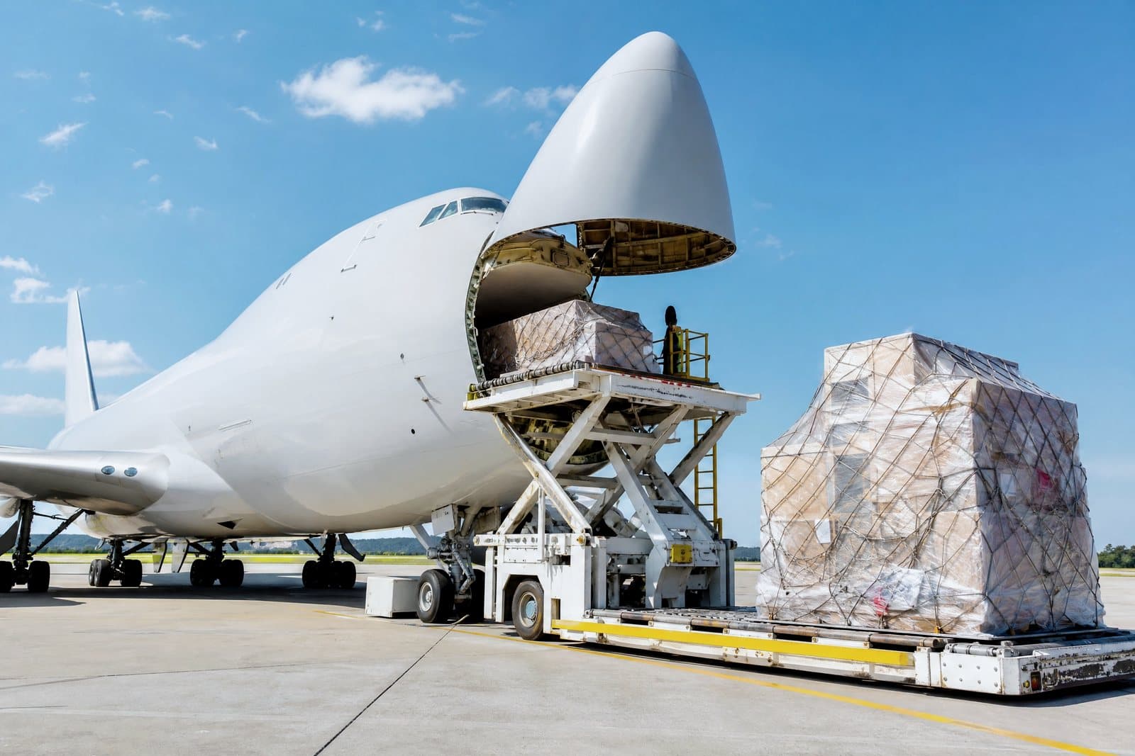 A 747 freighter's nose door swung open on the tarmac while ground crew load ULD pallets for uplift