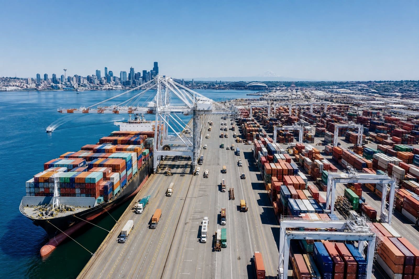 Aerial view of a container terminal: vessel at berth, gantry cranes, and container stacks